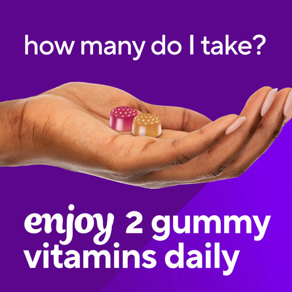 Two pink and orange VF Women's Multi Gummy vitamins held in a hand with text suggesting to enjoy two gummy vitamins daily.