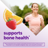 A smiling, middle-aged woman jogging outdoors, beside orange and strawberry graphics and 'supports bone health' text for Calcium + D3 Gummy.