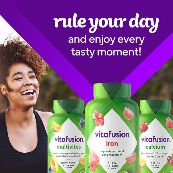 Woman smiling outdoors next to a vitafusion Iron Gummy bottle.