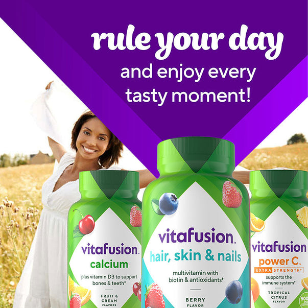 Adult woman smiling with arms open in a sunny field, promoting vitafusion Hair, Skin & Nails Gummy supplements.