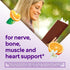 Smiling blonde woman reading a book outdoors with orange slices, text overlay 'for nerve, bone, muscle and heart support*'.